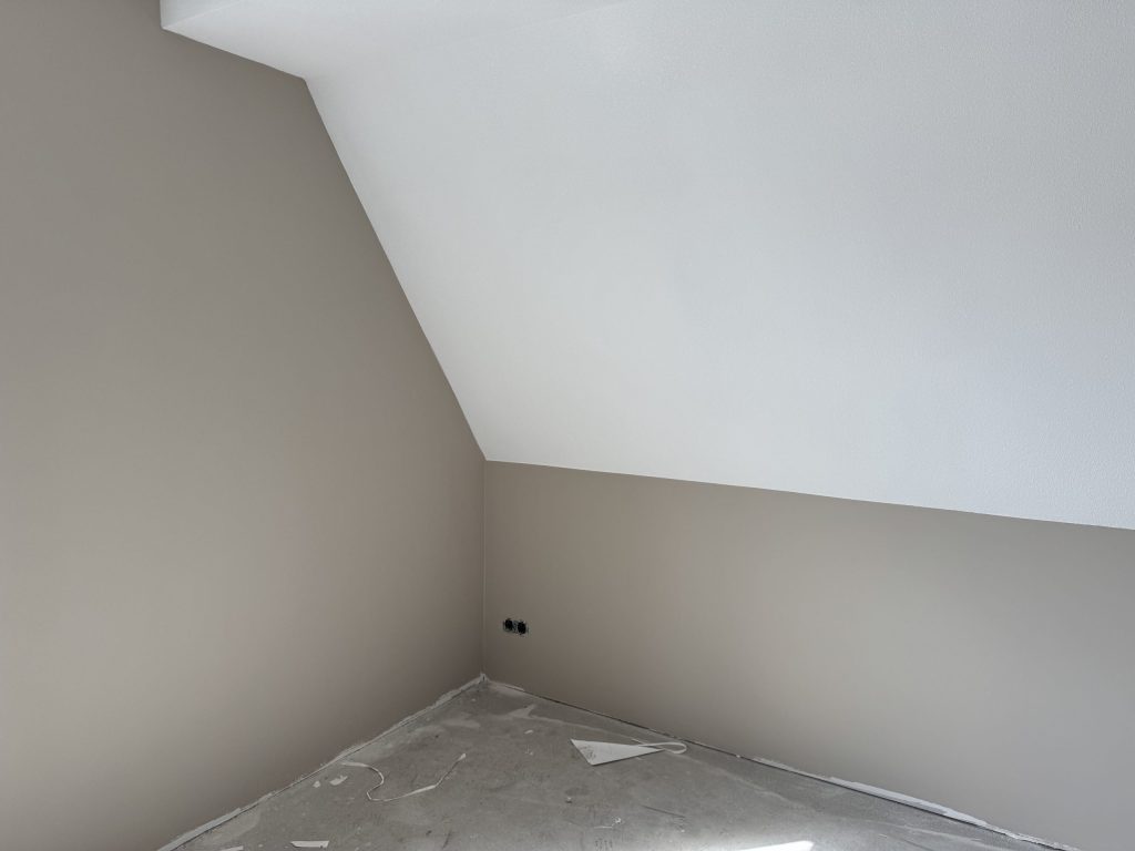 Zolderkamer in een nieuwbouwhuis met een schuine wand en pas gesausde muren